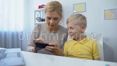 快乐的母亲和儿子一起在智能手机上玩游戏，玩得开心，<strong>APP</strong>